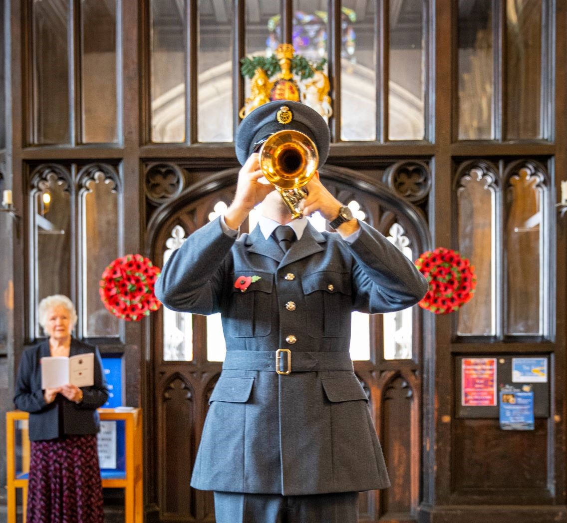 Image shows RAF musicians playing the bugle horn inside a church.